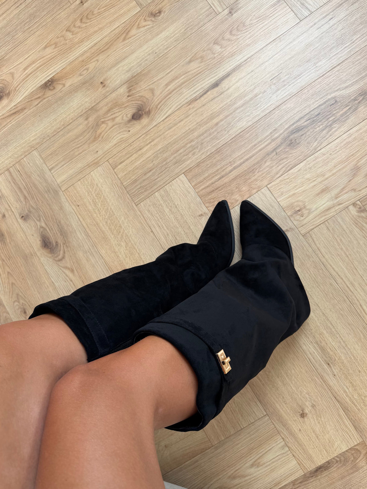 Women's black knee-high boots with pointed toes, buckle straps and low heels