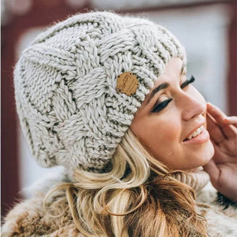Women's chunky cable knit beanie hat with turn-up cuff and front label detail