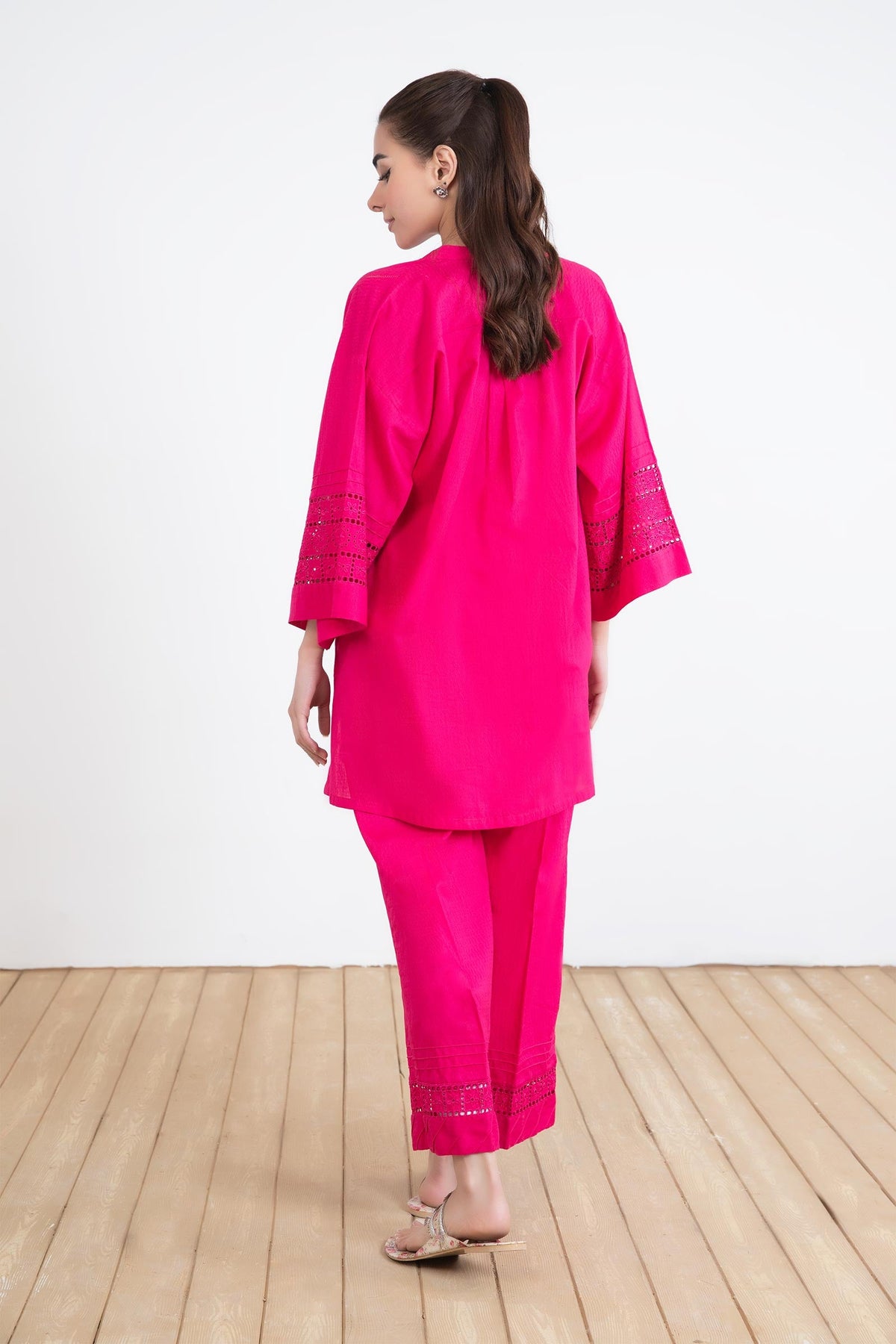 Women's bright pink two-piece tunic suit with lace-trimmed sleeves and matching trousers