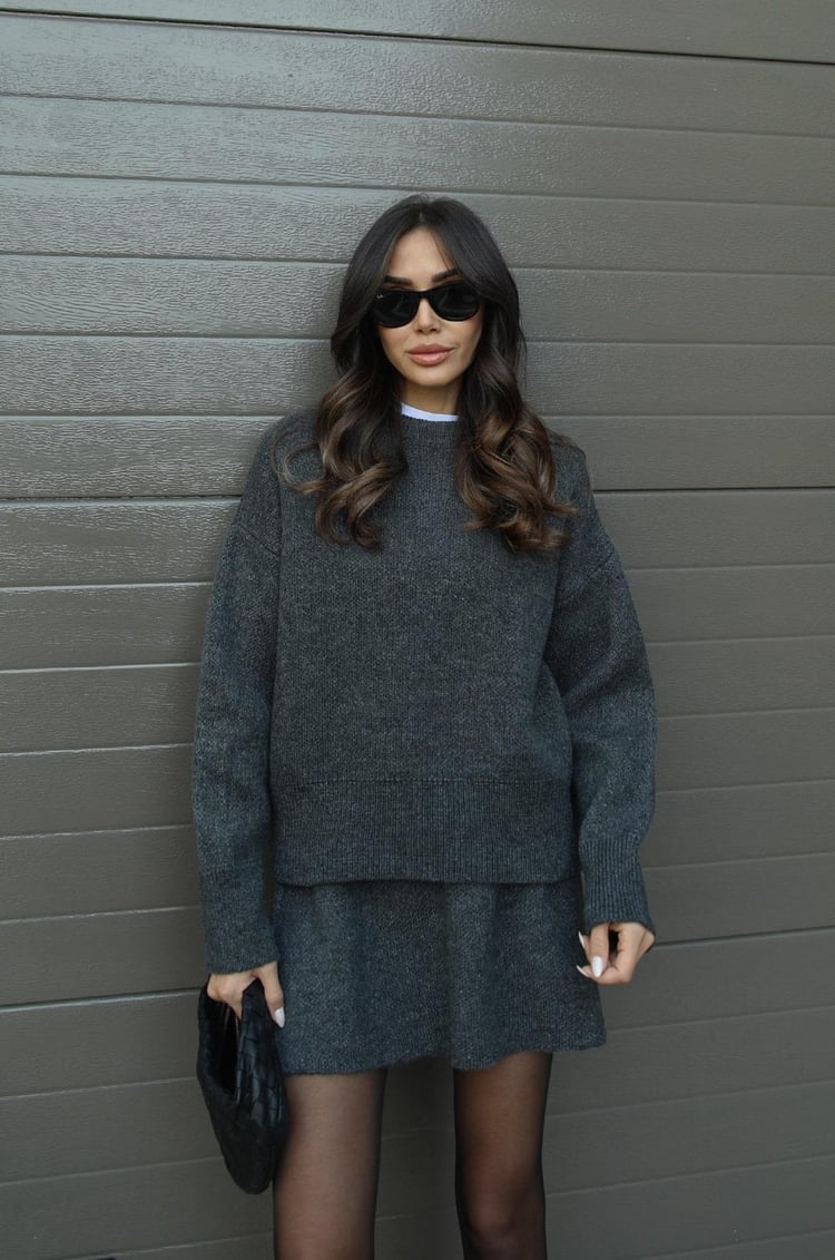 Woman wearing a plain knitted jumper and mini skirt set