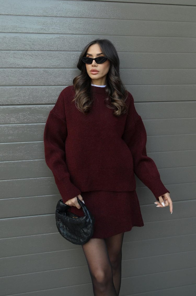 Woman wearing a plain knitted jumper and mini skirt set