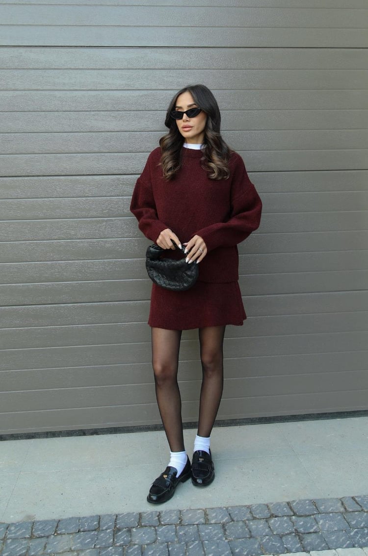 Woman wearing a plain knitted jumper and mini skirt set