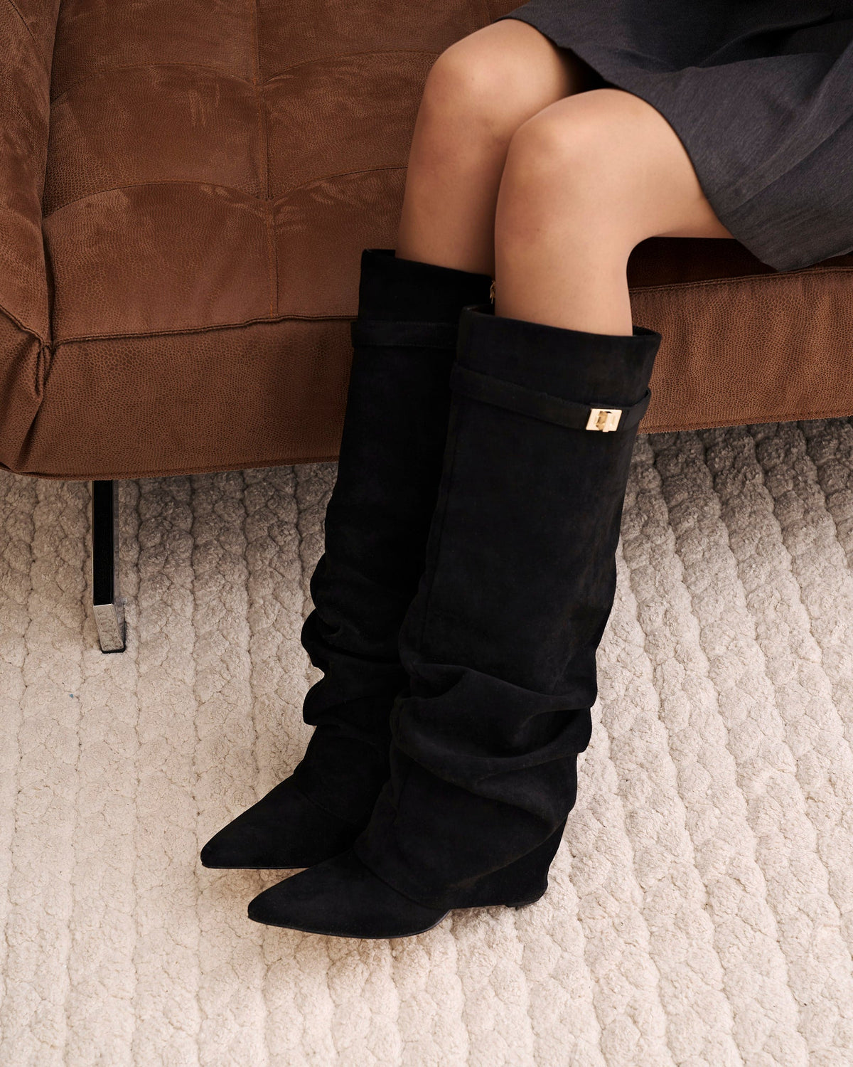 Black women's slouchy knee-high boots with pointed toes and gold-tone strap details