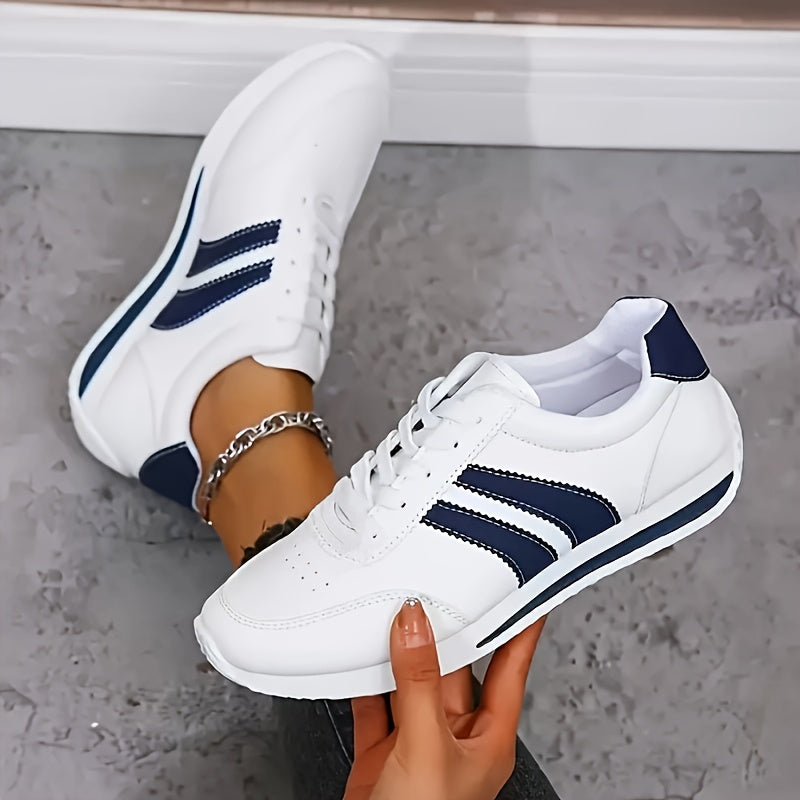 Women's white lace-up sneakers with navy side stripes and flat soles