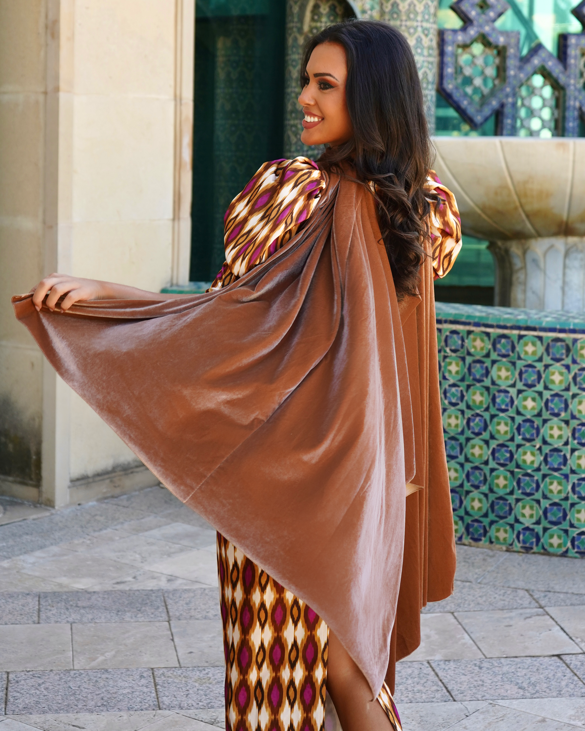 Woman wearing a burgundy draped multi-way cape with a cowl neckline