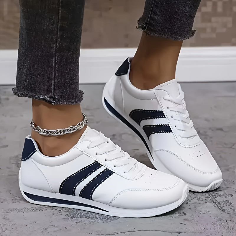 Women's white lace-up sneakers with navy side stripes and flat soles