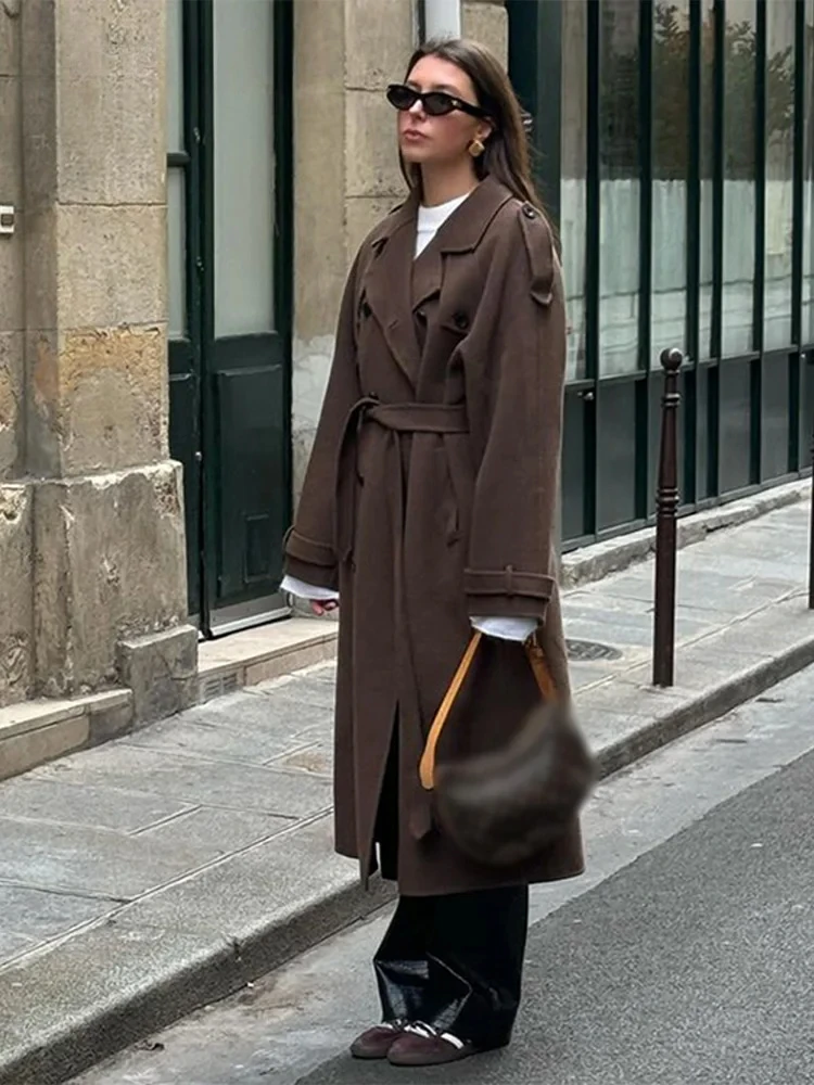Woman wearing a long double-breasted belted trench coat with lapels