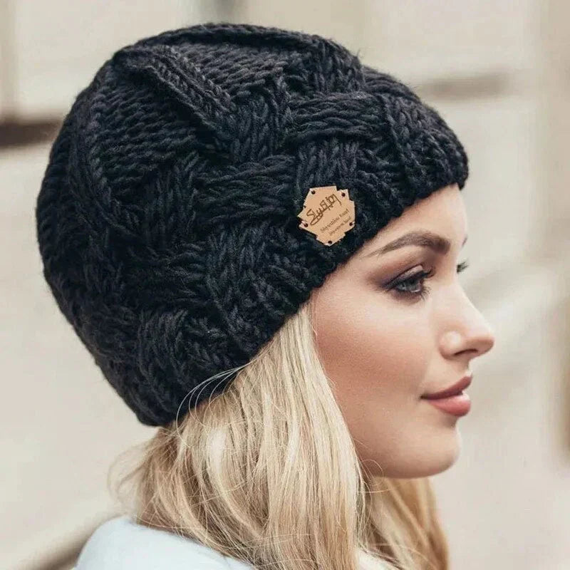 Women's chunky cable knit beanie hat with turn-up cuff and front label detail