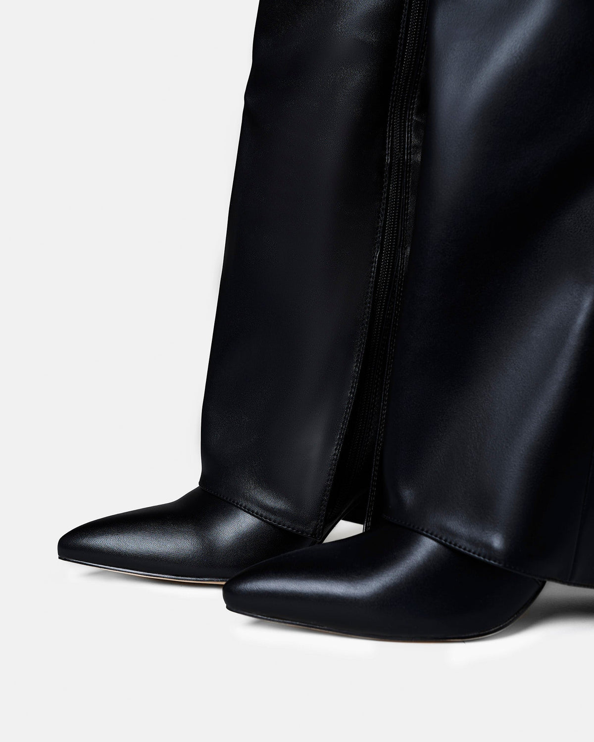 Black knee-high boots with pointed toes, low heels and buckle strap detail