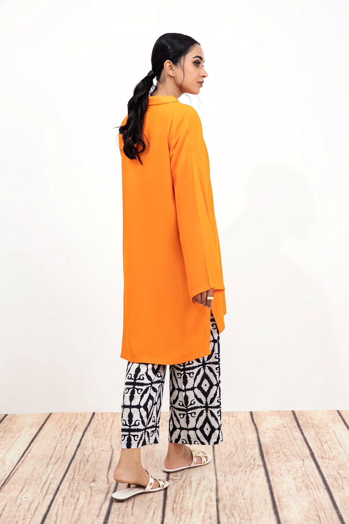 Woman wearing an orange long-sleeve tunic with patterned trousers