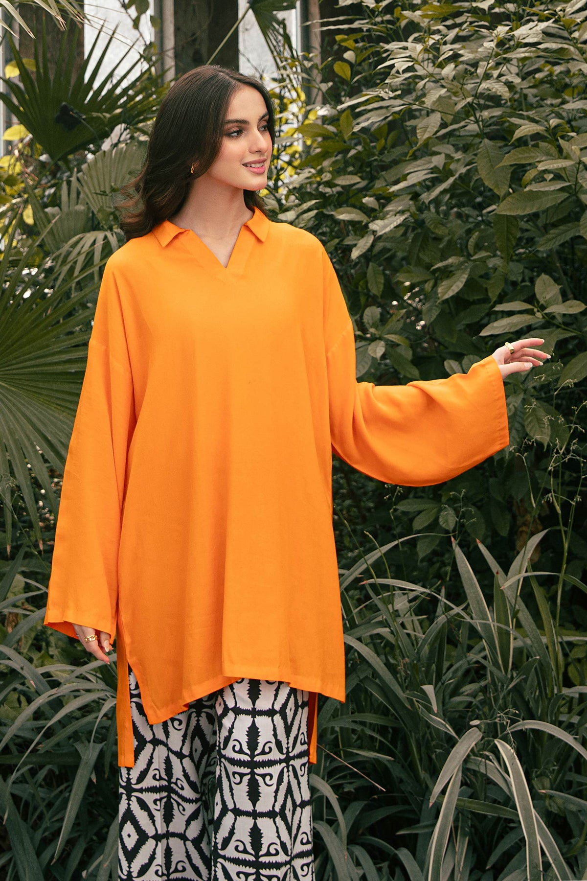 Woman wearing an orange long-sleeve tunic with patterned trousers
