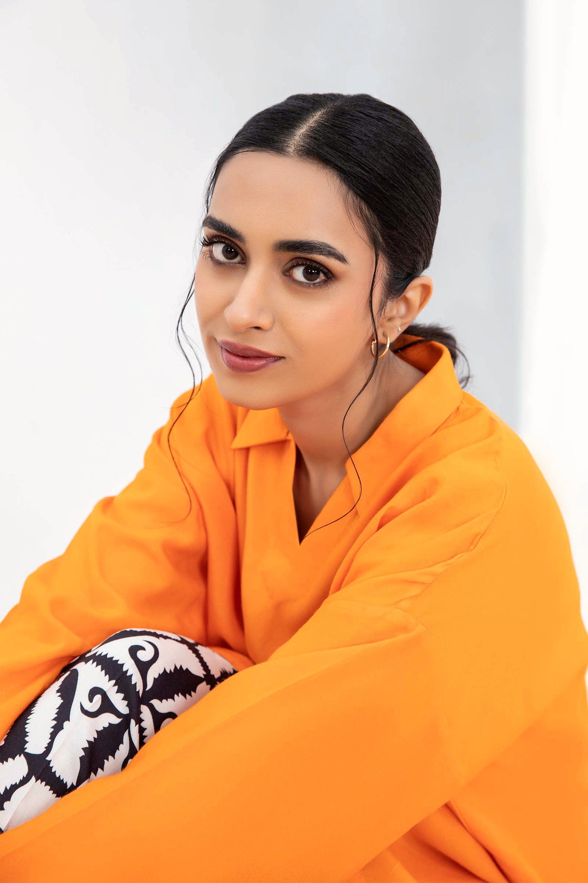 Woman wearing an orange long-sleeve tunic with patterned trousers