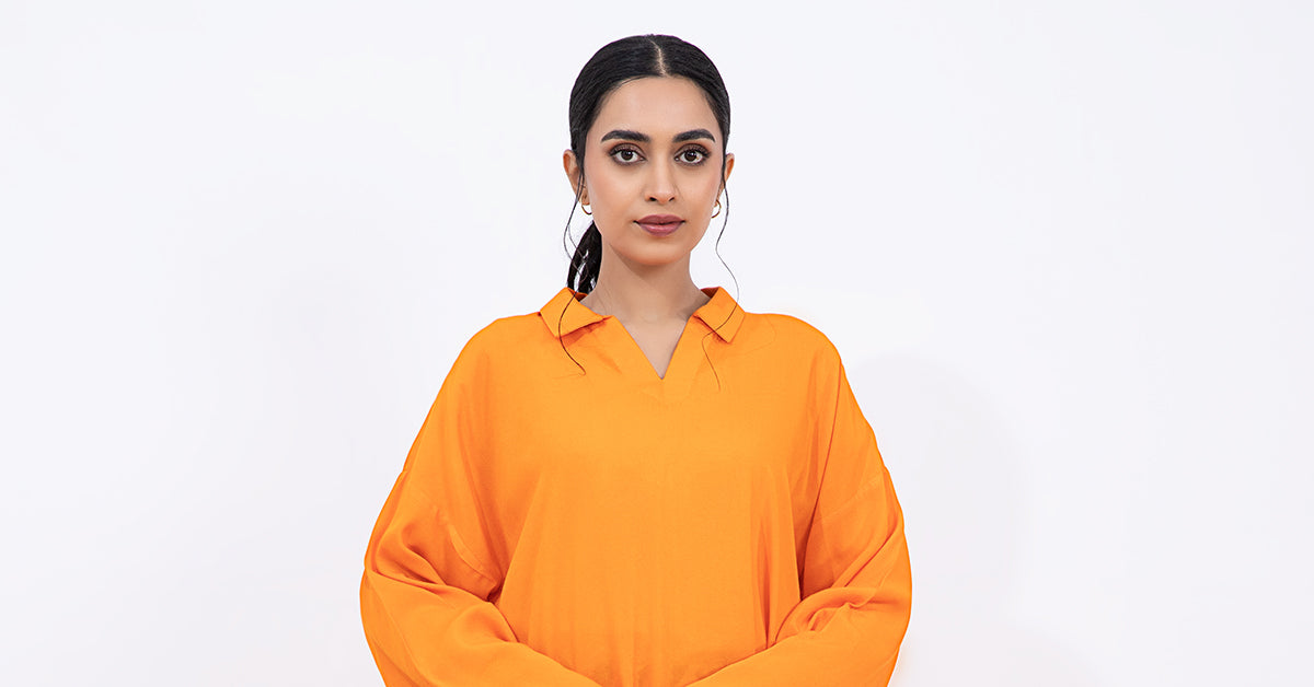 Woman wearing an orange long-sleeve tunic with patterned trousers