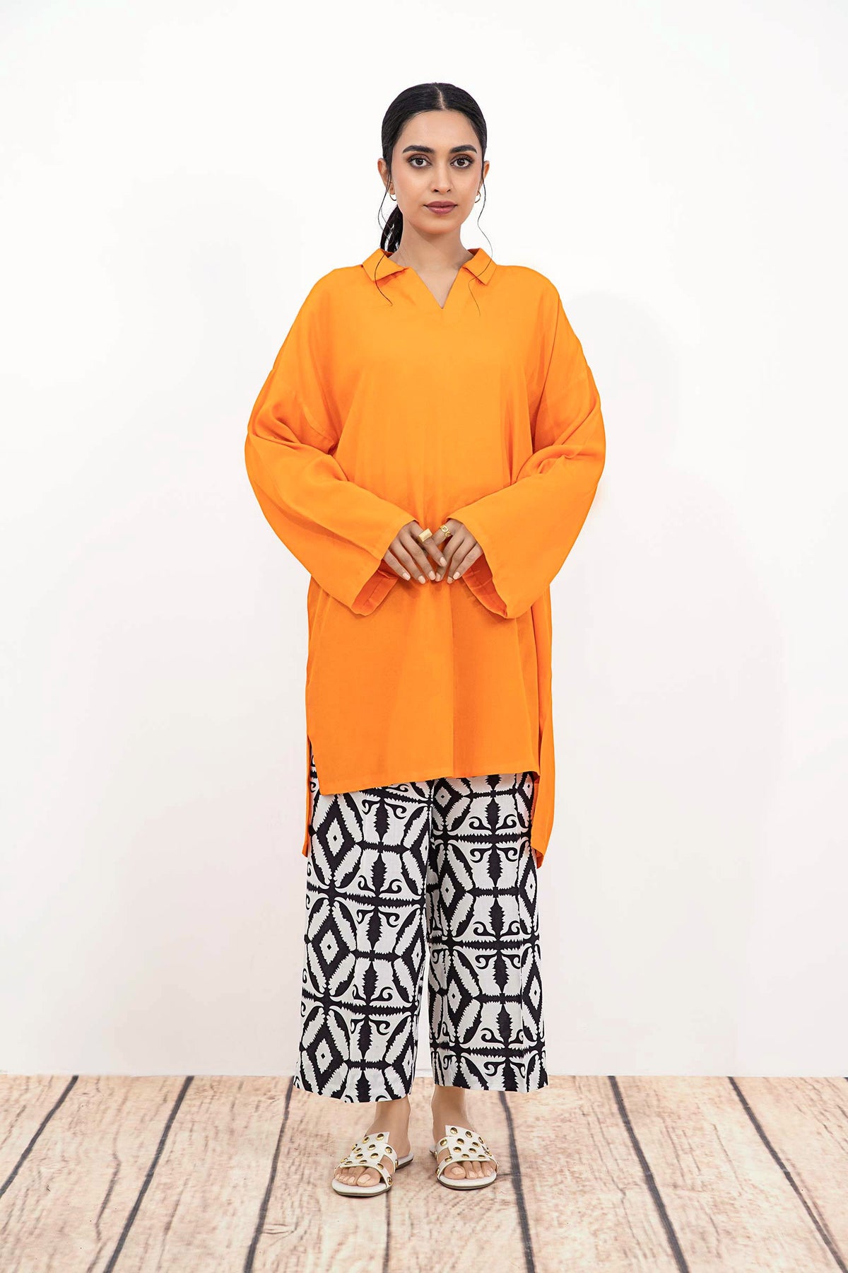 Woman wearing an orange long-sleeve tunic with patterned trousers