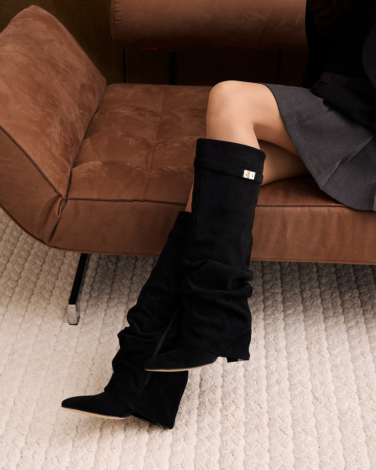 Black women's slouchy knee-high boots with pointed toes and gold-tone strap details
