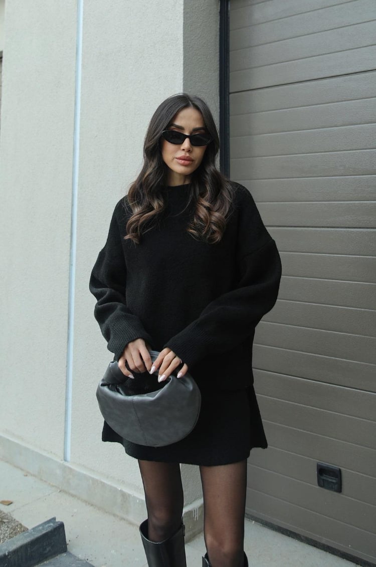 Woman wearing a plain knitted jumper and mini skirt set